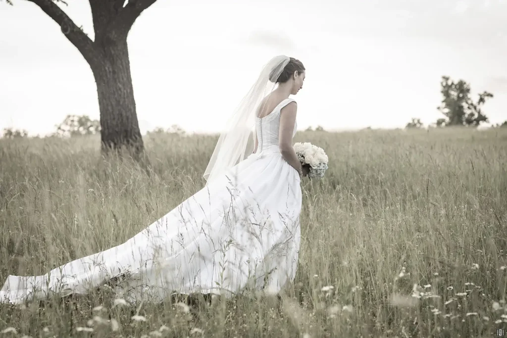 Woman standing in a field wearing a wedding dress